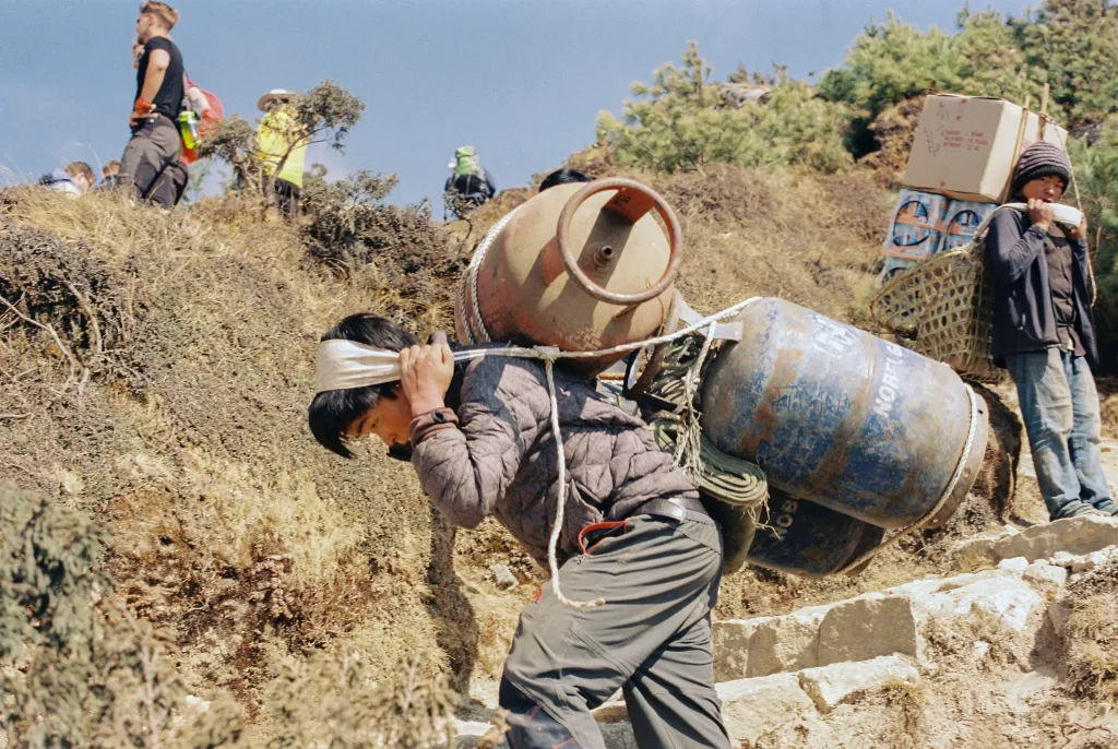 Boy carries 3 gas canisters up a mountain