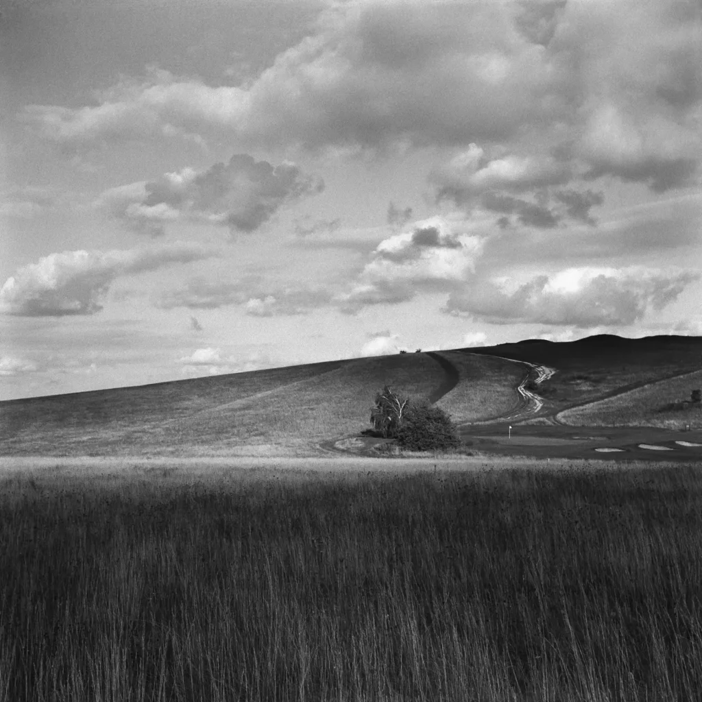 Grassland leading to a hill with large shadows from the clouds