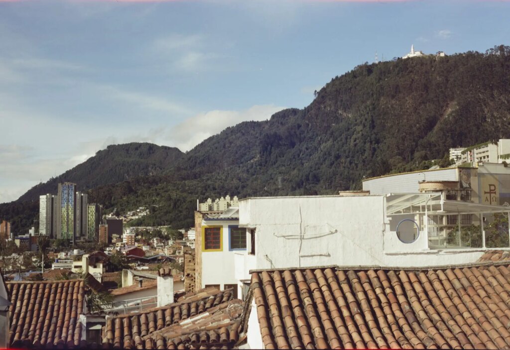 The skyline of Bogotá, especially the Candelaria district and downtown. On the top of a green mountain is Monserrate church.