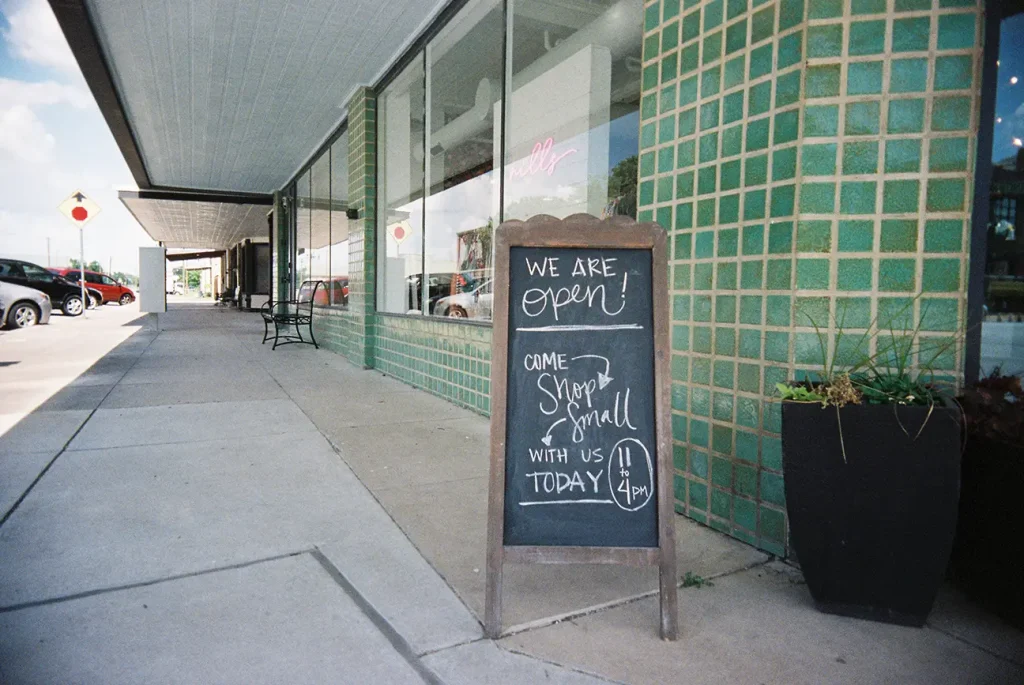 Open sign on sidewalk near a shop taken with the White Slim Angel 35mm plastic point and shoot film camera.