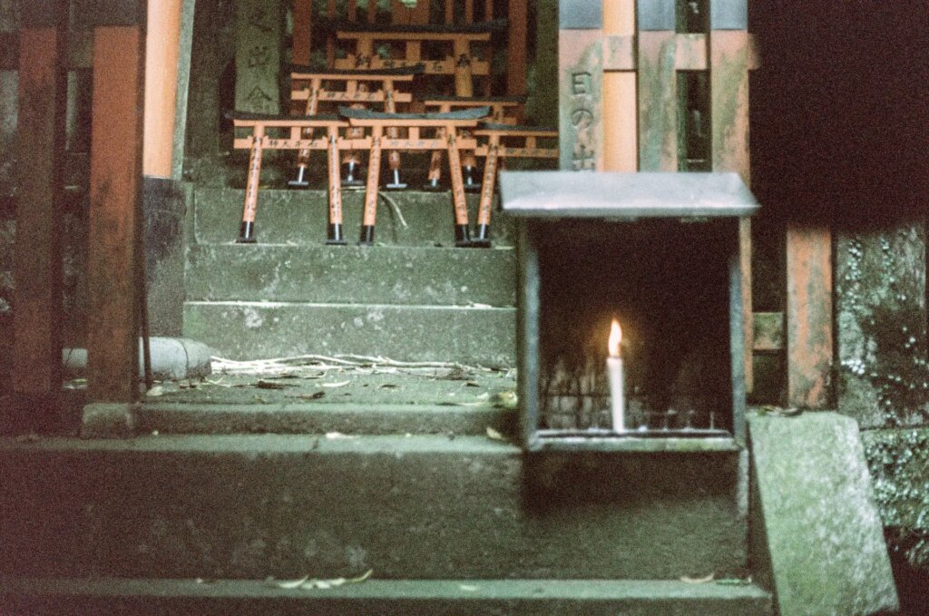 A shrine with miniature torii gates and a single lit candle