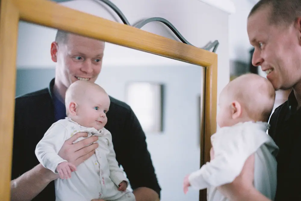 Man holding baby in mirror photographed with Contax T2