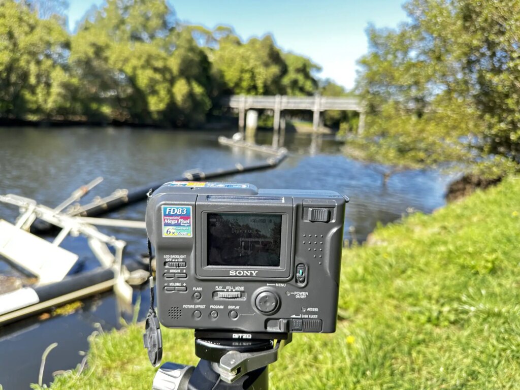 MVC-FD83 camera on a tripod in front of a bridge and river