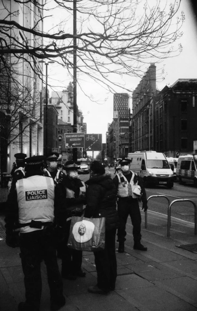 Police holding back a woman attempting to pass the line.