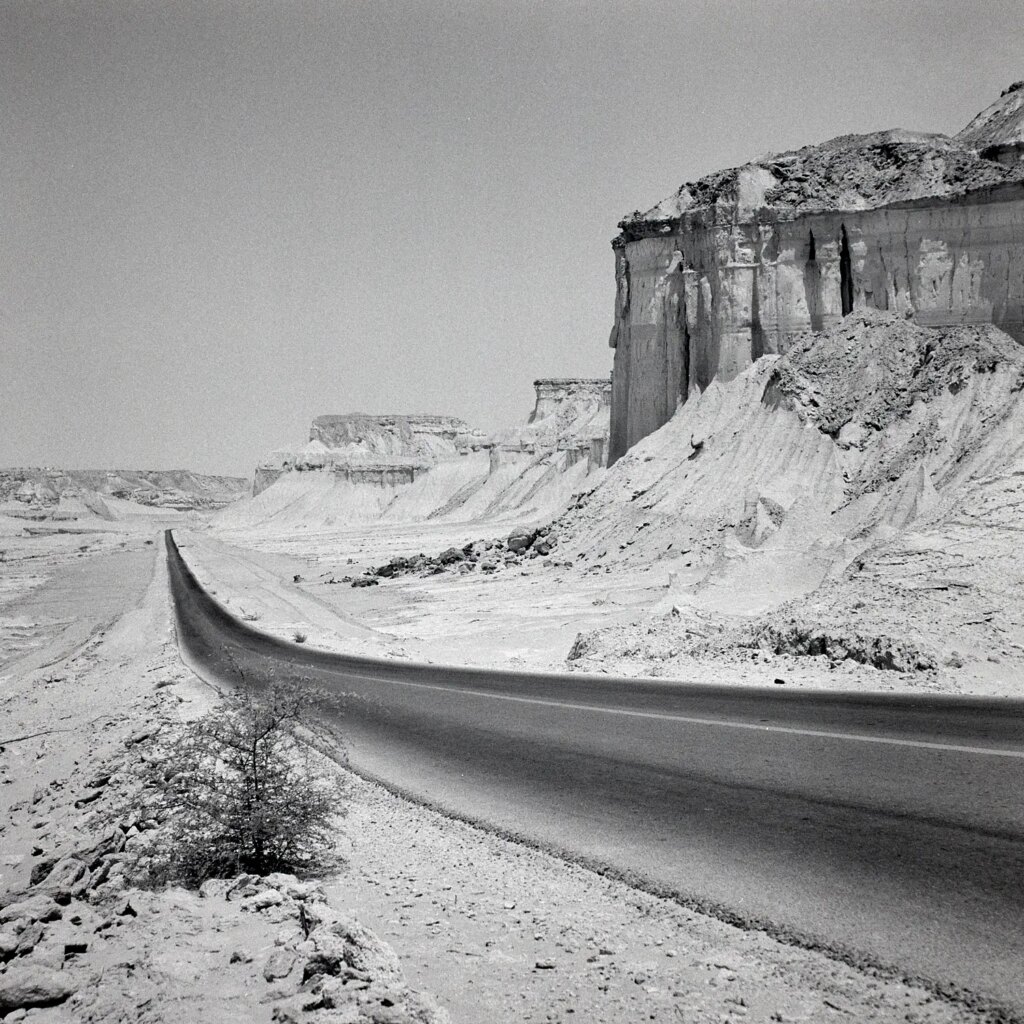 A curved road next to high, steep cliffs.