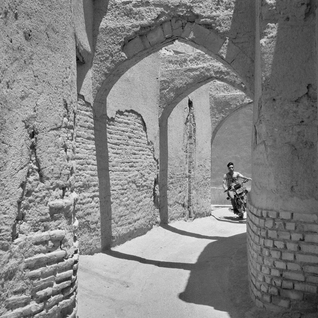 Young male riding a motorcycle with no helmet on narrow streets of the old town.