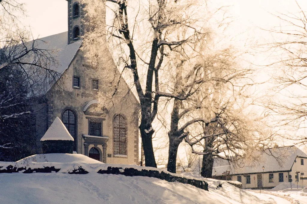 Photo of a church and some trees covered in sunlight taken on slide film.