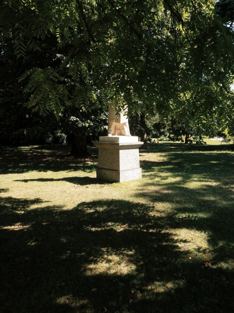 A statue, partially covered by leaves.