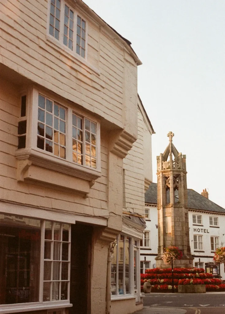 Old overhanging timber shop with flower-laden war memorial in background