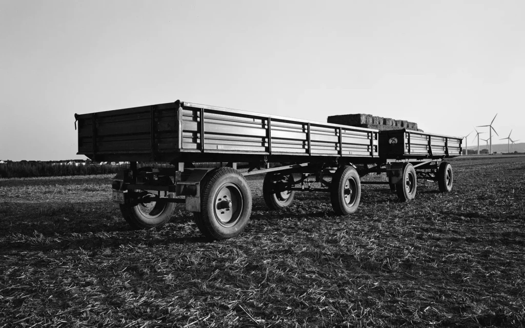 two farming trailers parked on a field