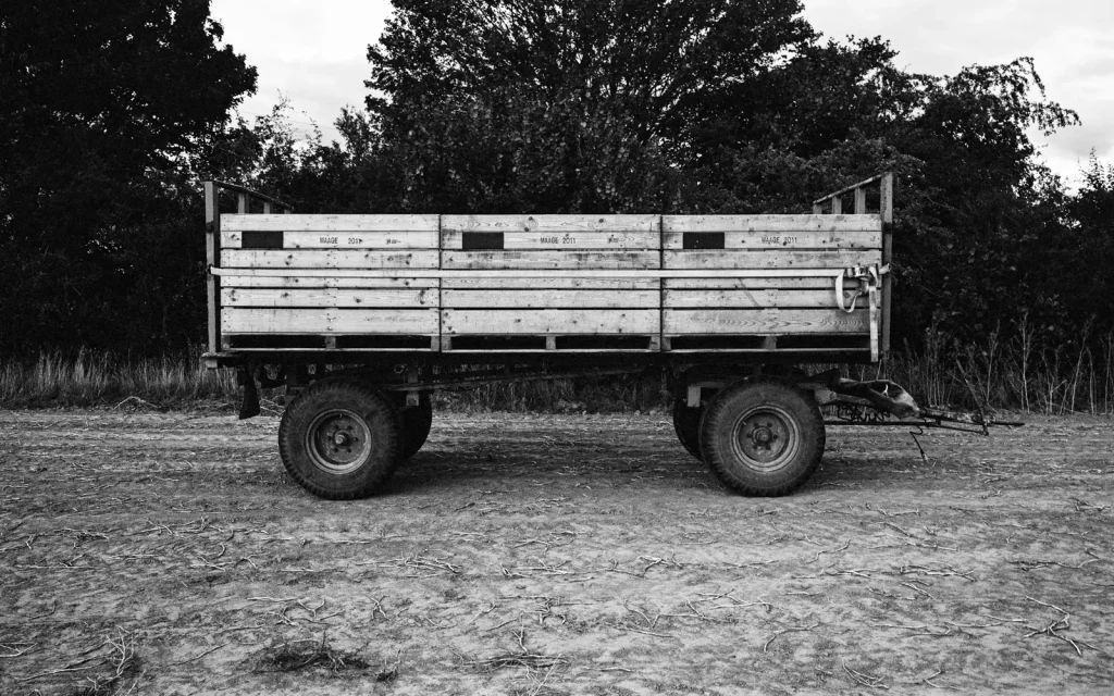 empty farming trailer parked at the side of a potato field