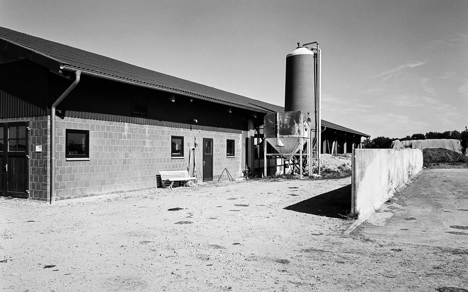 A modern cow barn with a silo tower on its side.