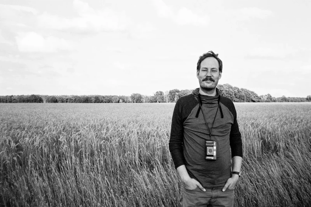 a man standing infront of a grain field
