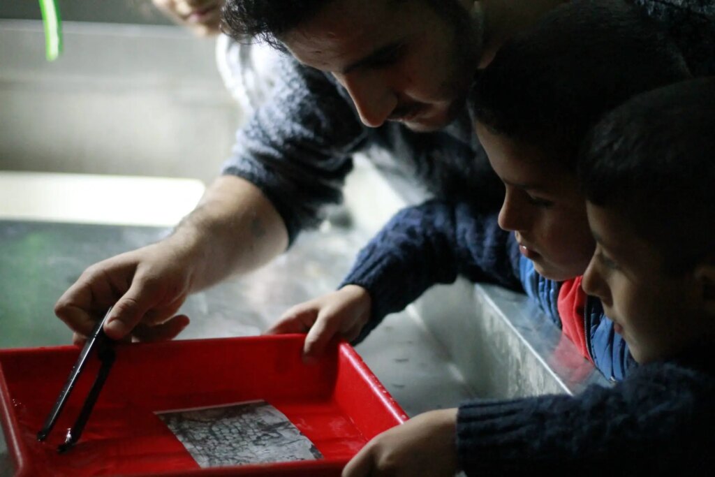 children practice printing photos in darkroom workshop