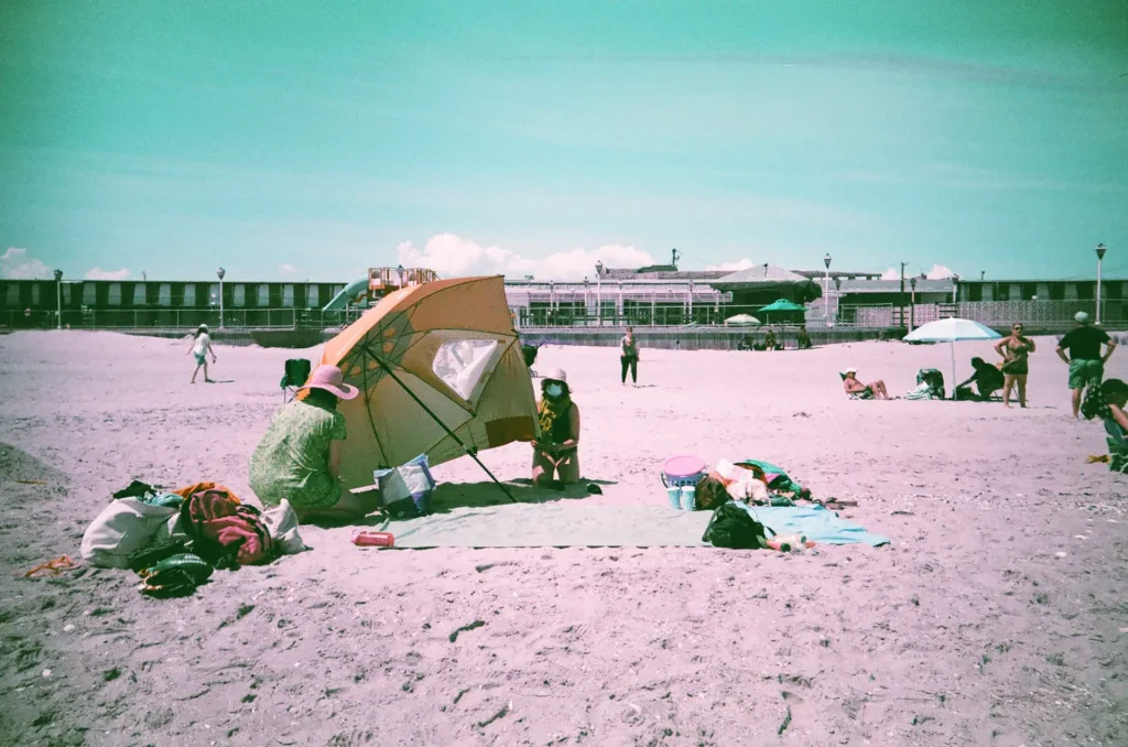 People on a beach setting up an umbrella.