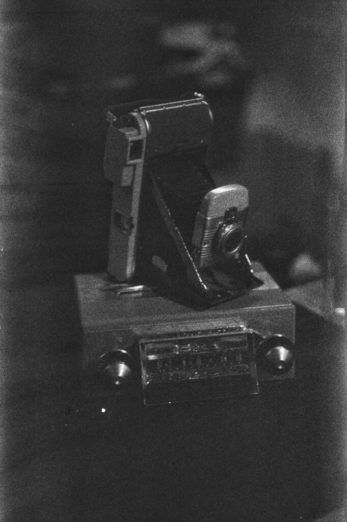 Dense, low-contrast negative of a polaroid land camera atop a vintage radio