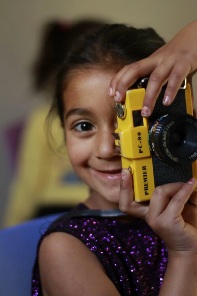 portrait of a girl holds a camera to her face to take a photo