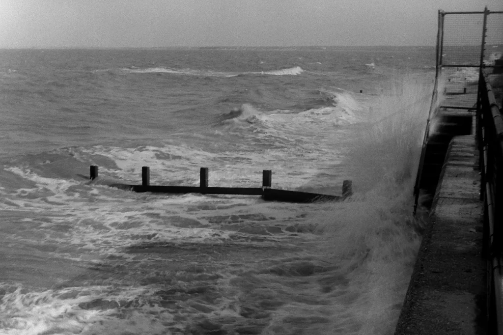 b/w photo of waves crashing against sea wall