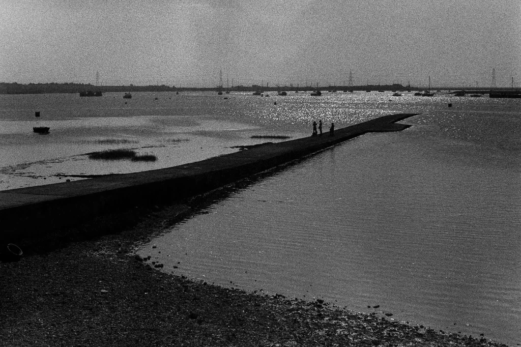 a b/w photo of a river harbour with children standing on the walkway