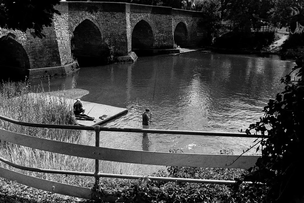 b/w photo of two men fishing in a river