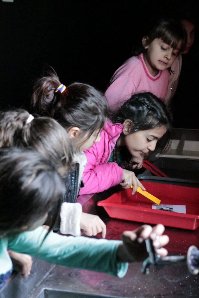 girls pratice printing photos in darkroom workshop