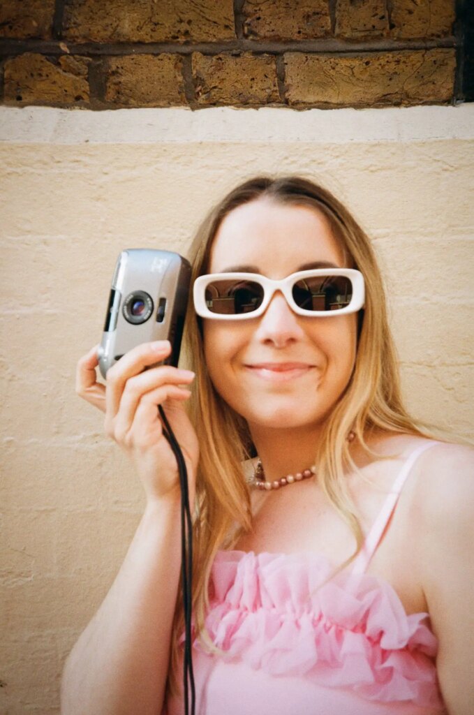 Emma Lloyd, co-host of Grainsplaining pictured with her film camera