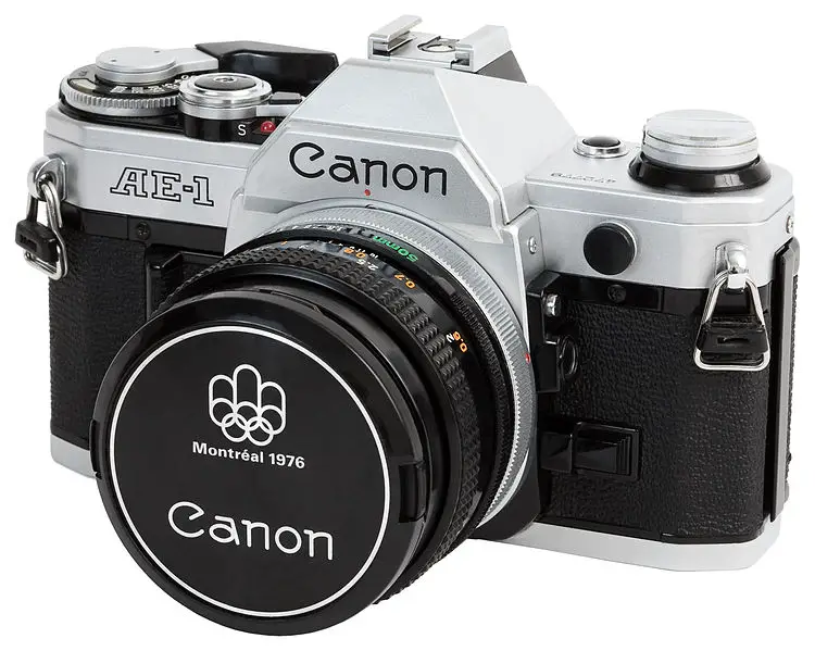 Canon AE-1 with 50mm f1.8 attached. A special Montreal 1976 Olympics lens cap adorns the front of the lens.