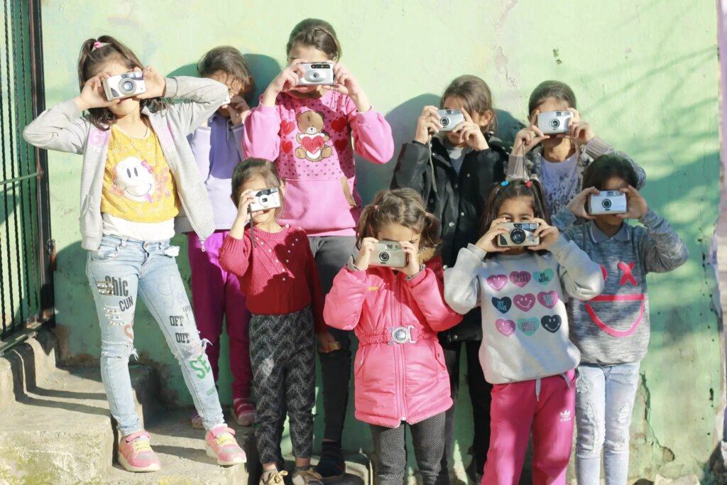 Children pose with cameras during darkroom workshop