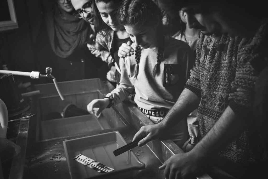 Students in darkroom learning to process and print analogue film photos