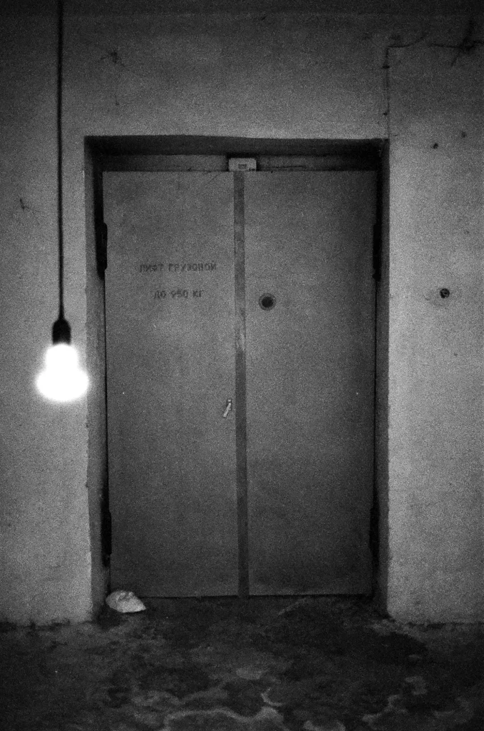 clack and white photo of doorway with hanging light bulb
