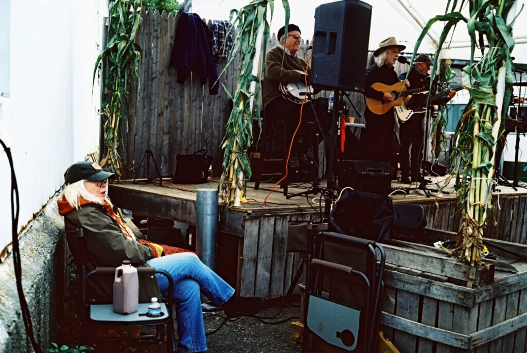 woman in a chair listening to a band playing on stage outside