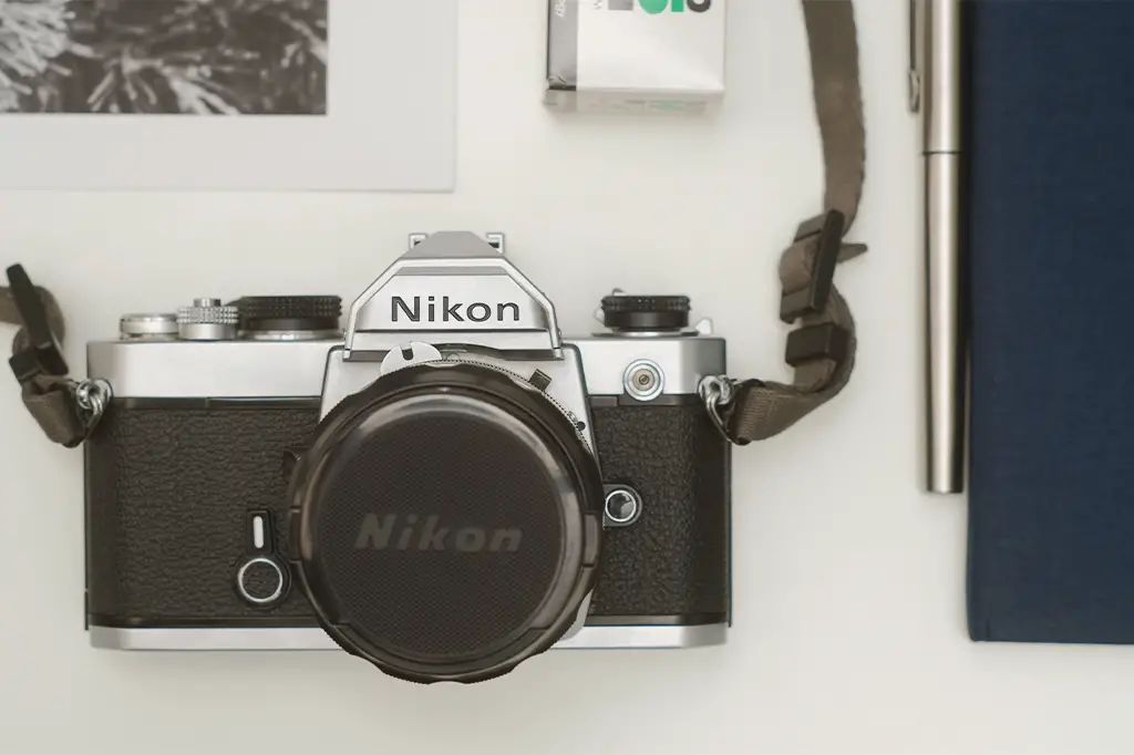 Nikon FM laid out on table with notebook and film