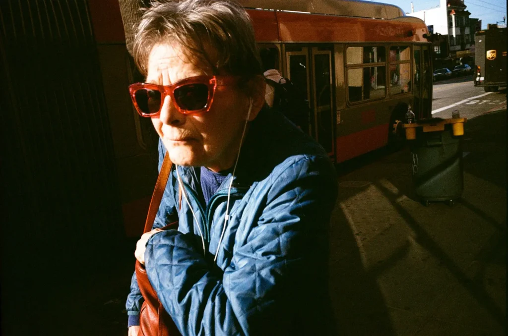 Lady with sunglasses and headphones walk away from a bus