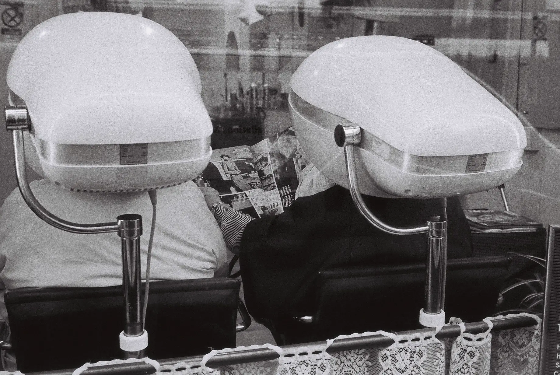 Two women in hairdresser under hairdryers