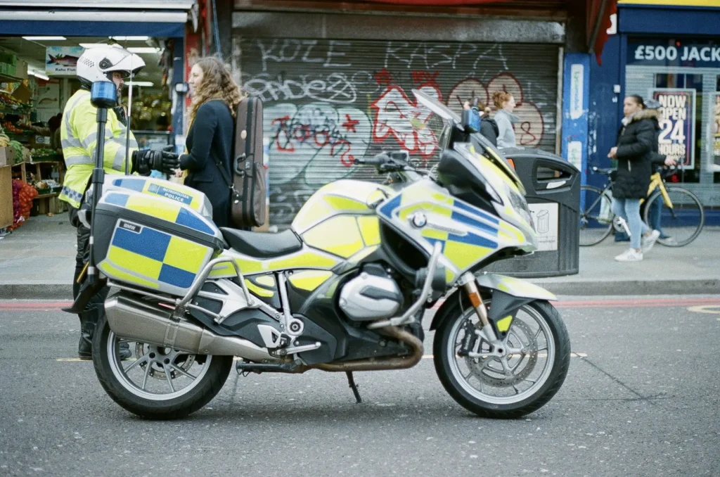 In the foreground is an empty police motorcycle. in the background and to the left is a dismounted motorcycle policeman talking to a protestor