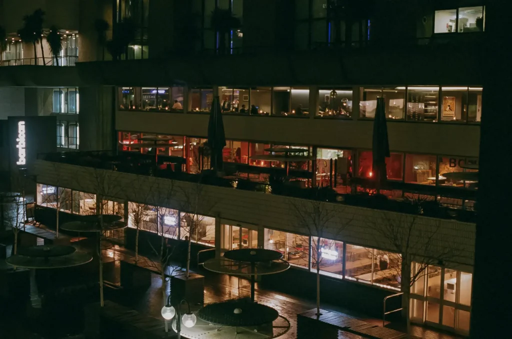 A night time view of a a multi-floor building with from the side angle about halfway up an adjacent building