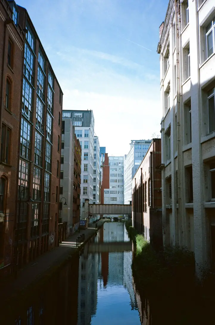 Mixture of Buildings Old and New, Red Brick and Limestone, with Reflections off the Canal running centrally between the corridor of buildings.