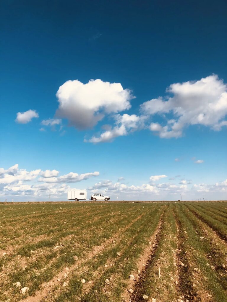 mobile darkroom trailer and car in the middle of the country under blue skies