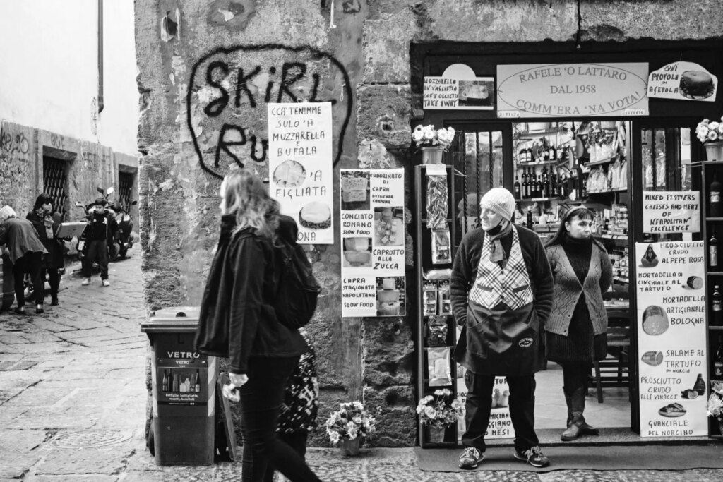 A shopkeeper watches the street for potential customers, or perhaps just out of boredom.