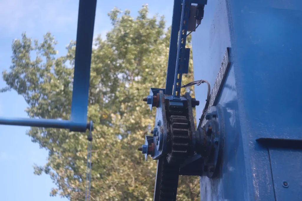 Closeup of a bridge-raising motor, with blurred trees in the distant background.