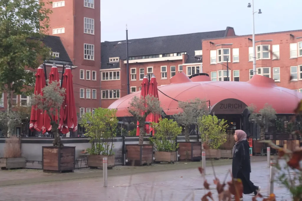 A woman walks among buildings around Mercatorplein, Amsterdam.