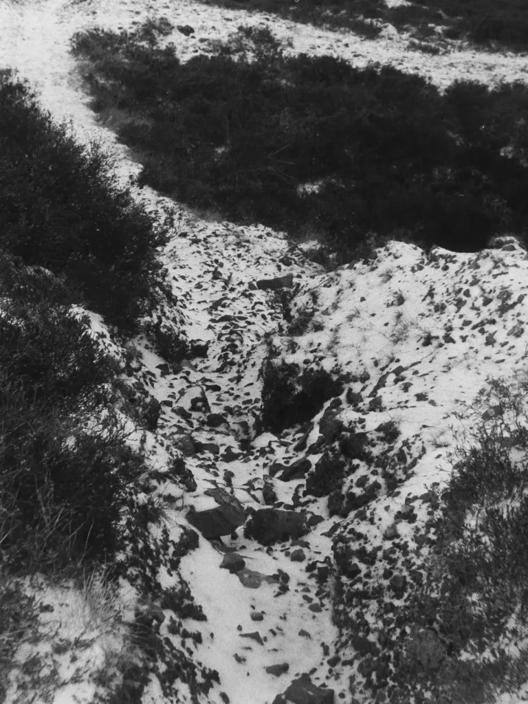 Looking down the valley side, slag eroded by water.