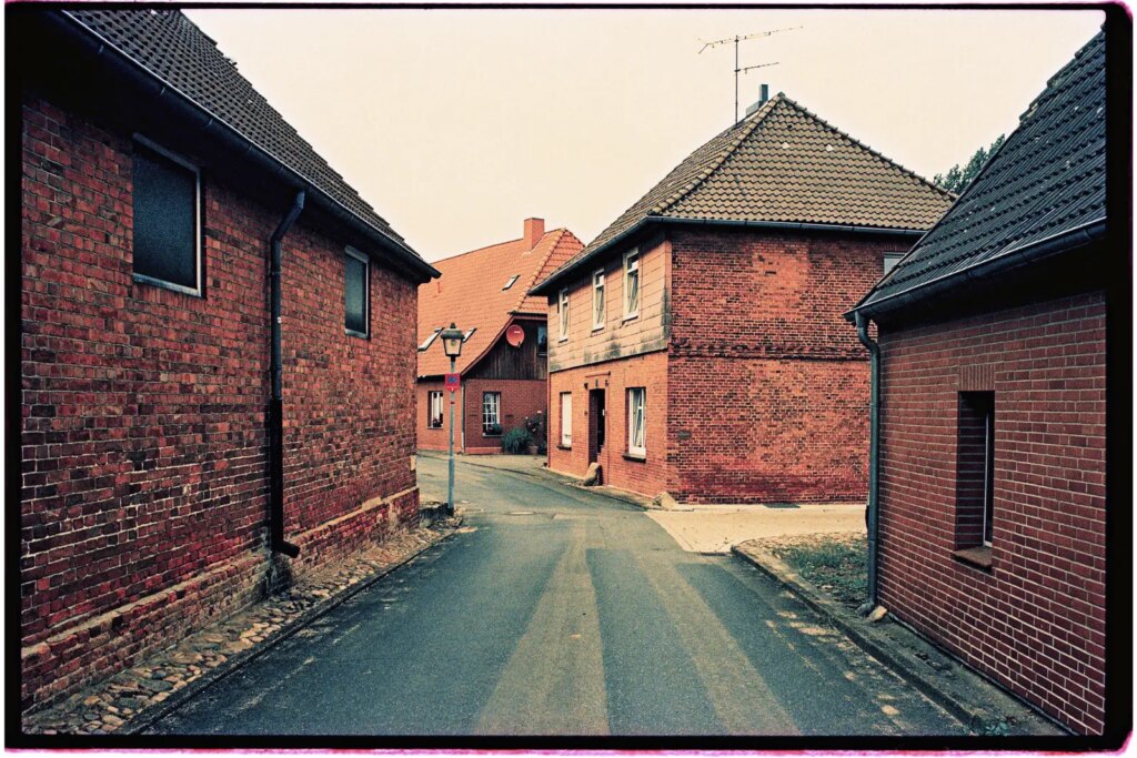 Several small brick houses along a narrow road, photograph shot on Fujichrome 64T II slide film.
