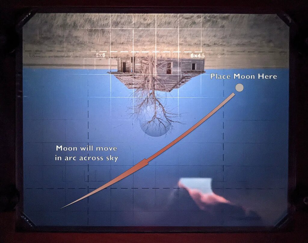 Large format ground glass of cabin in the prairie showing moon's path for eclipse