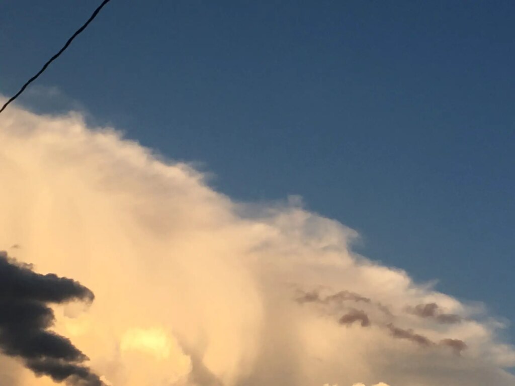 Bright cloud, blue sky, sliver of wire