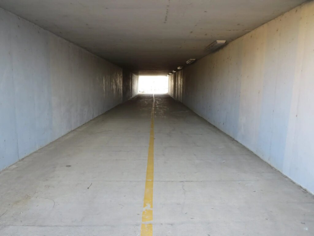 small tunnel with light at end, yellow stripe down middle of frame