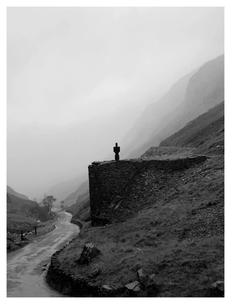 A statue overlooking a fog shrouded pass on the Lake District