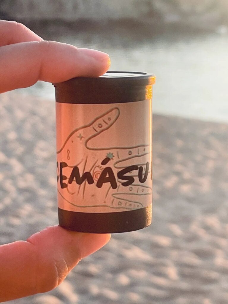 hand holding film canister on the beach