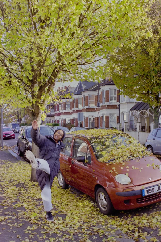 Autumn tree and car. Girl kicks the fallen leaves