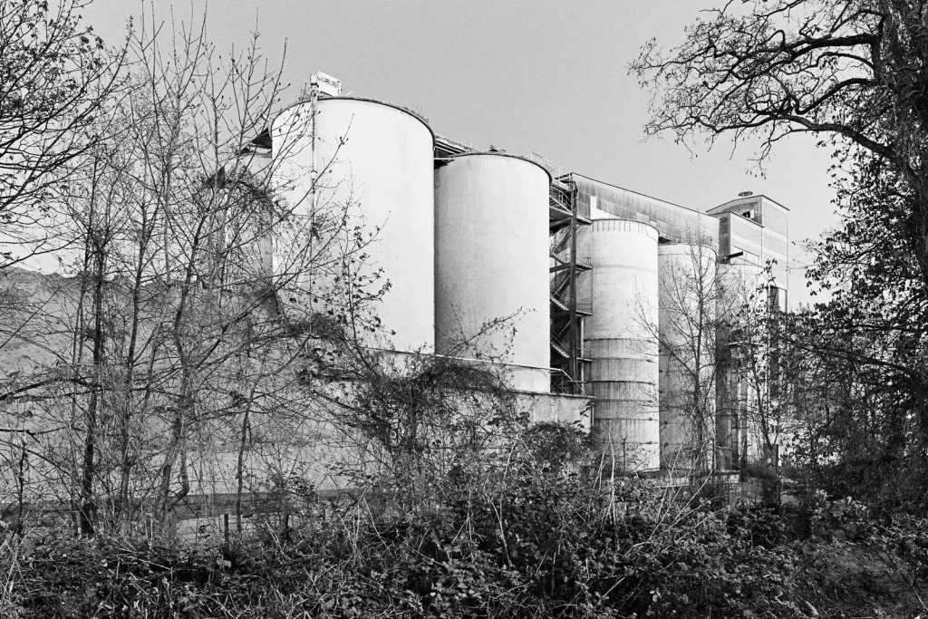 Black-and-white photographs of cement silos at the site of an abandoned factory.